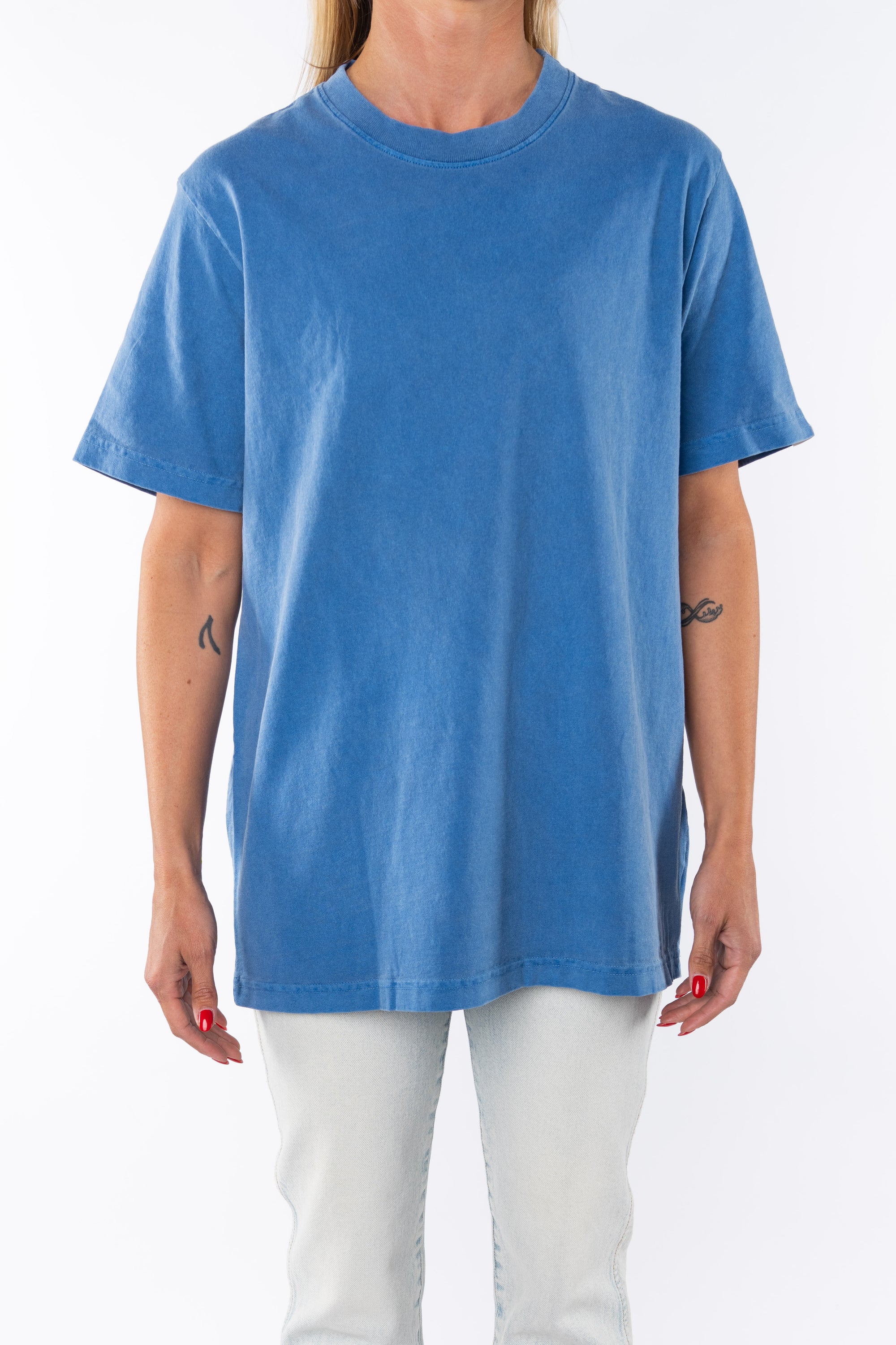 Woman wearing a beach blue t-shirt with light denim jeans on a white background