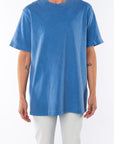 Woman wearing a beach blue t-shirt with light denim jeans on a white background