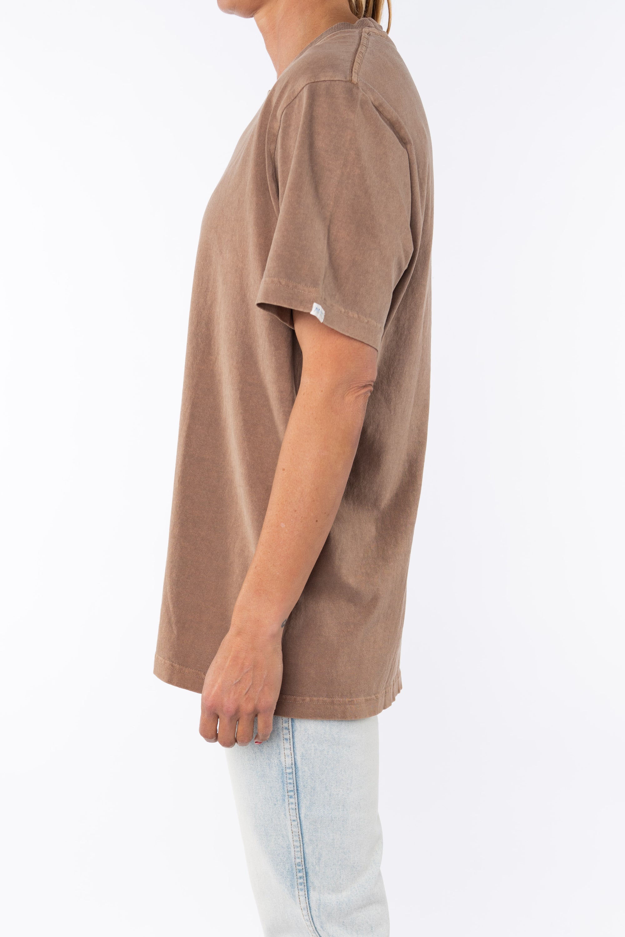 Woman wearing a brown beach t-shirt and light blue jeans on a white background