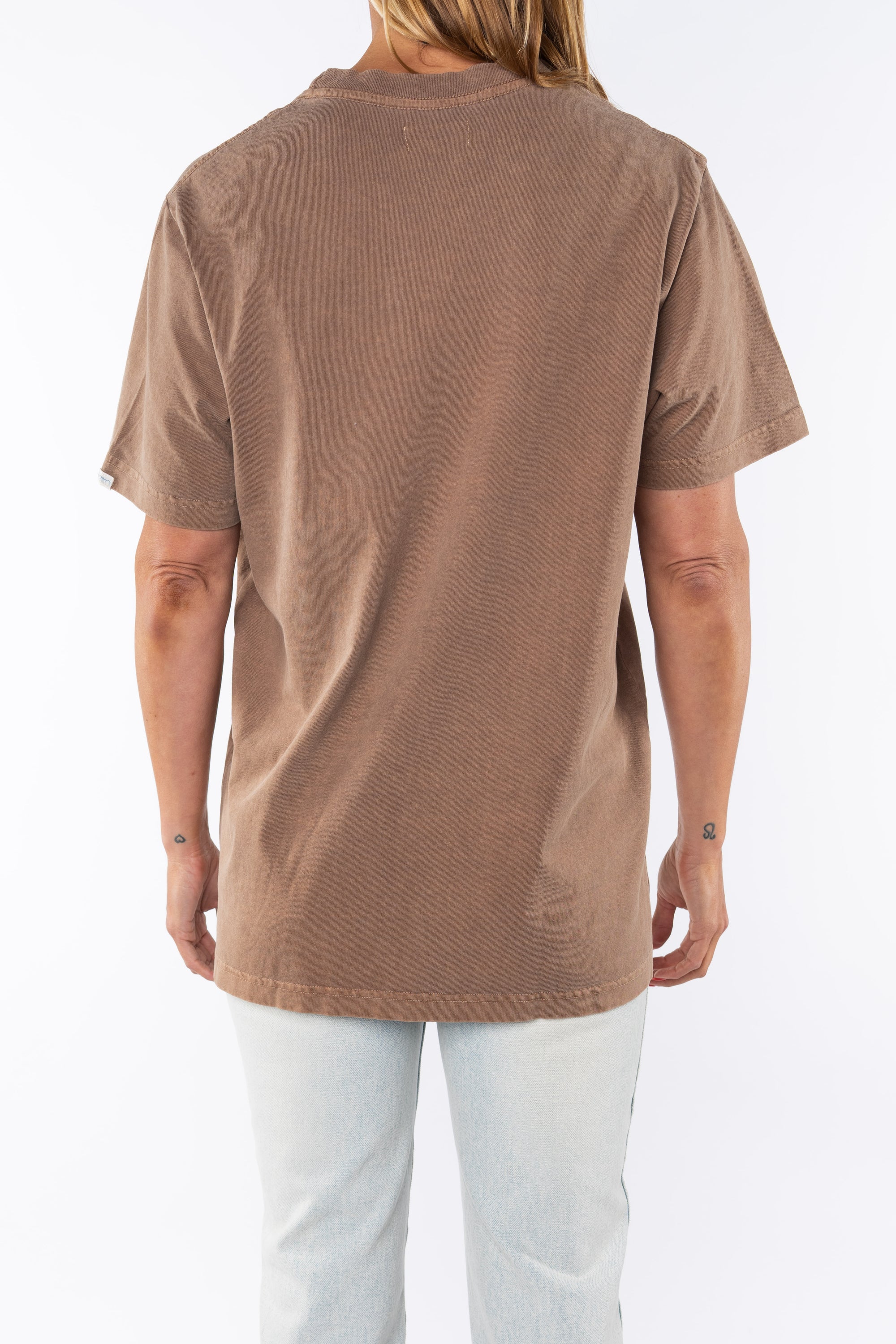 Back shot of a woman wearing Beach Crewneck T-shirt in Brownstone with Surf Jeans.