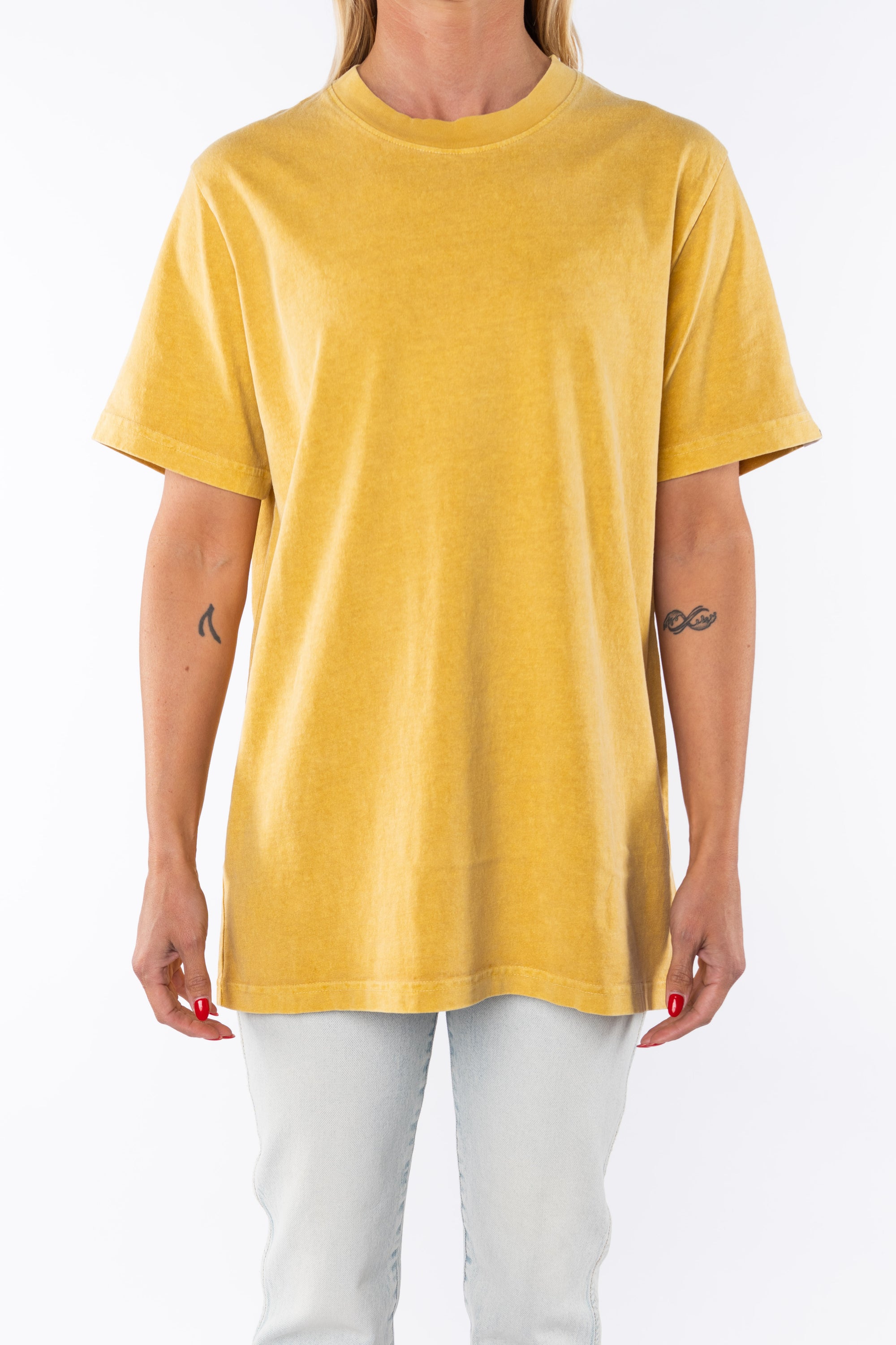 Woman wearing a sunrise yellow beach t-shirt and light denim jeans on a white background