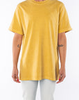 Woman wearing a sunrise yellow beach t-shirt and light denim jeans on a white background