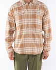 Man wearing Bucky Split Hem Shirt Jacket in White/Beige Plaid with Beach Crewneck T-shirt Brownstone with Army Green Day pants. 