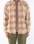 Man wearing Bucky Split Hem Shirt Jacket in White/Beige Plaid with Beach Crewneck T-shirt Brownstone with Army Green Day pants. 