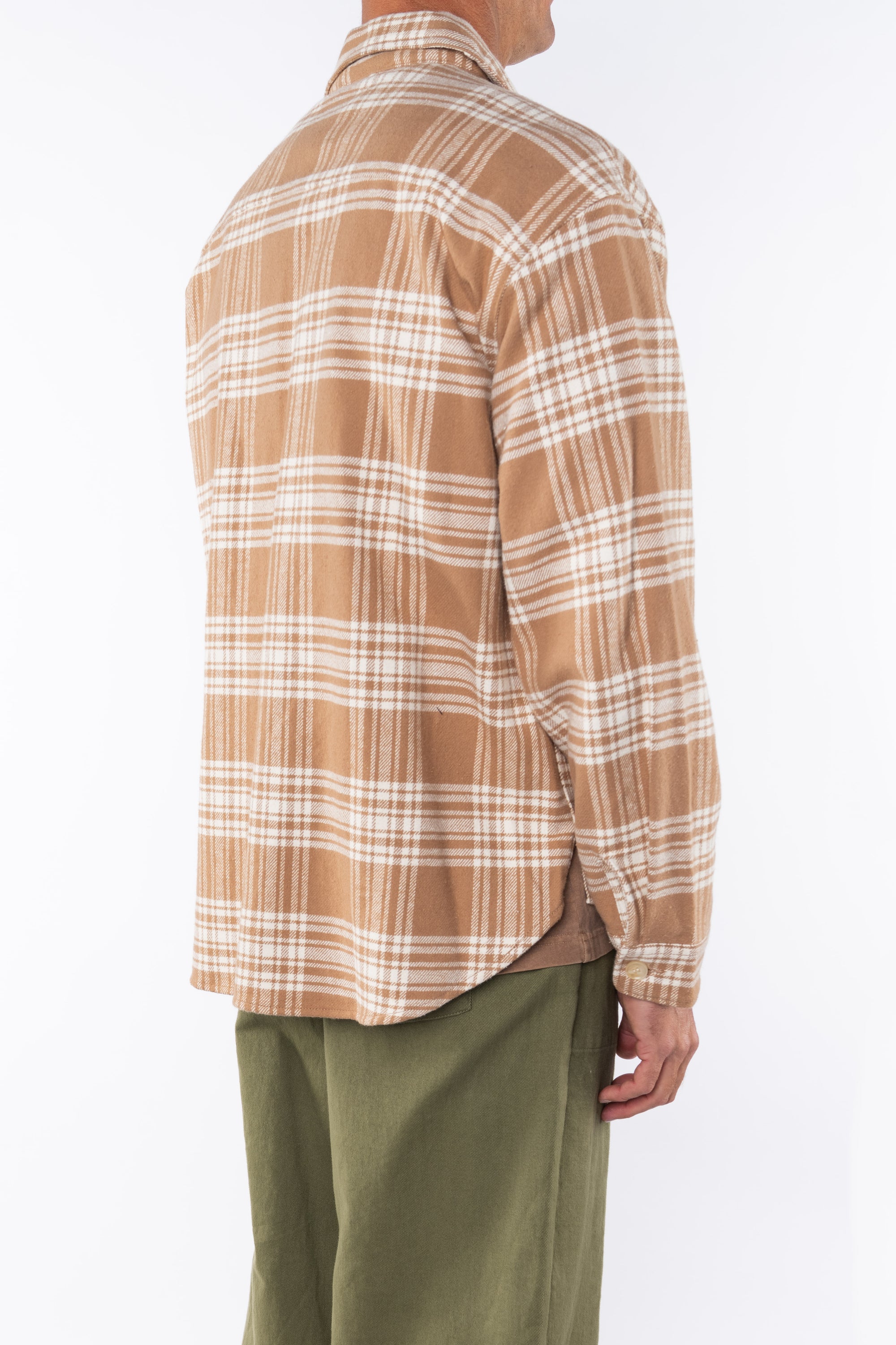 Side back view of a man wearing bucky beige plaid shirt jacket with army green day pants on a white background