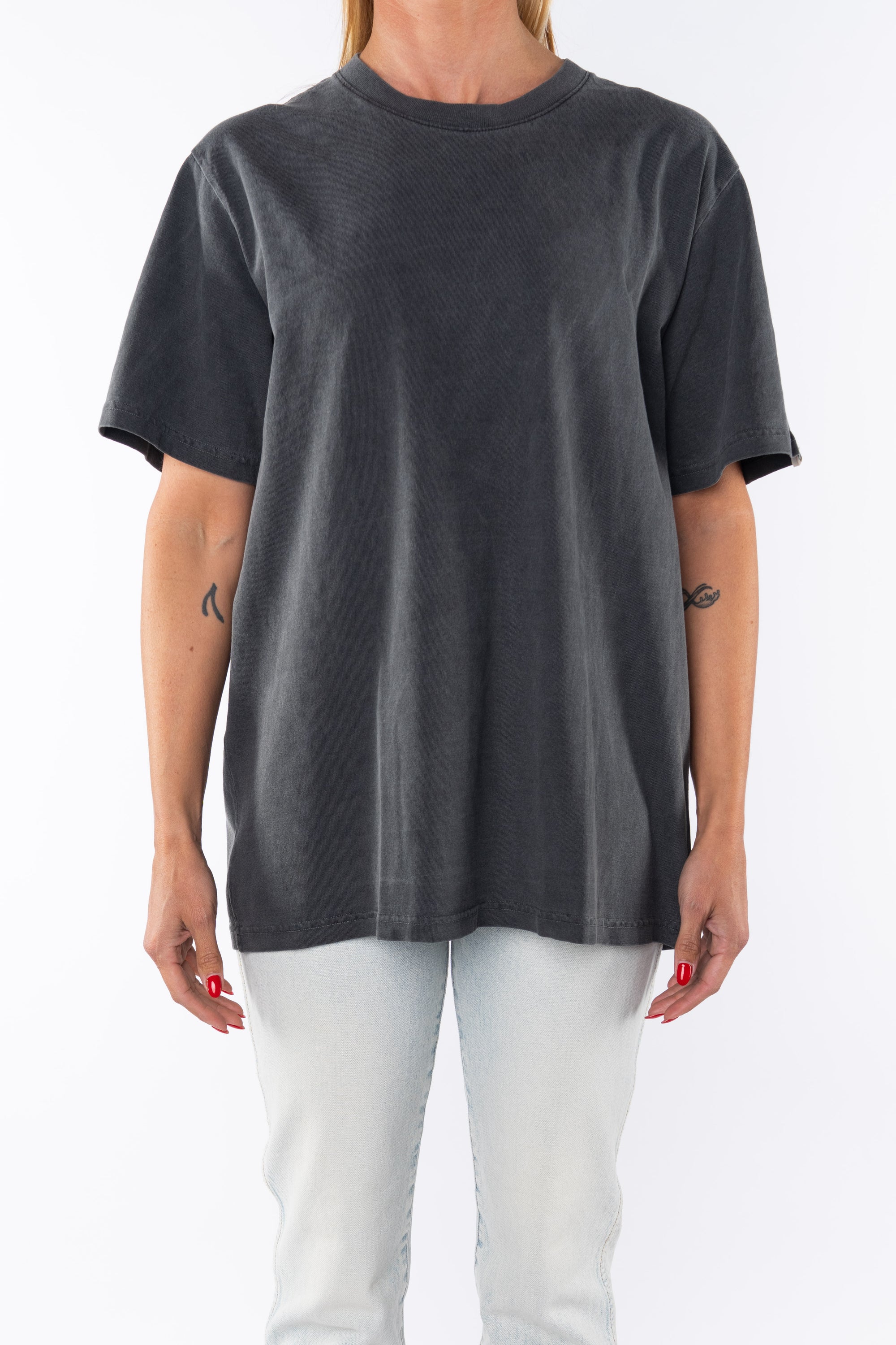 Woman wearing a dark gray beach t-shirt and light denim jeans on a white background