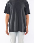 Woman wearing a dark gray beach t-shirt and light denim jeans on a white background