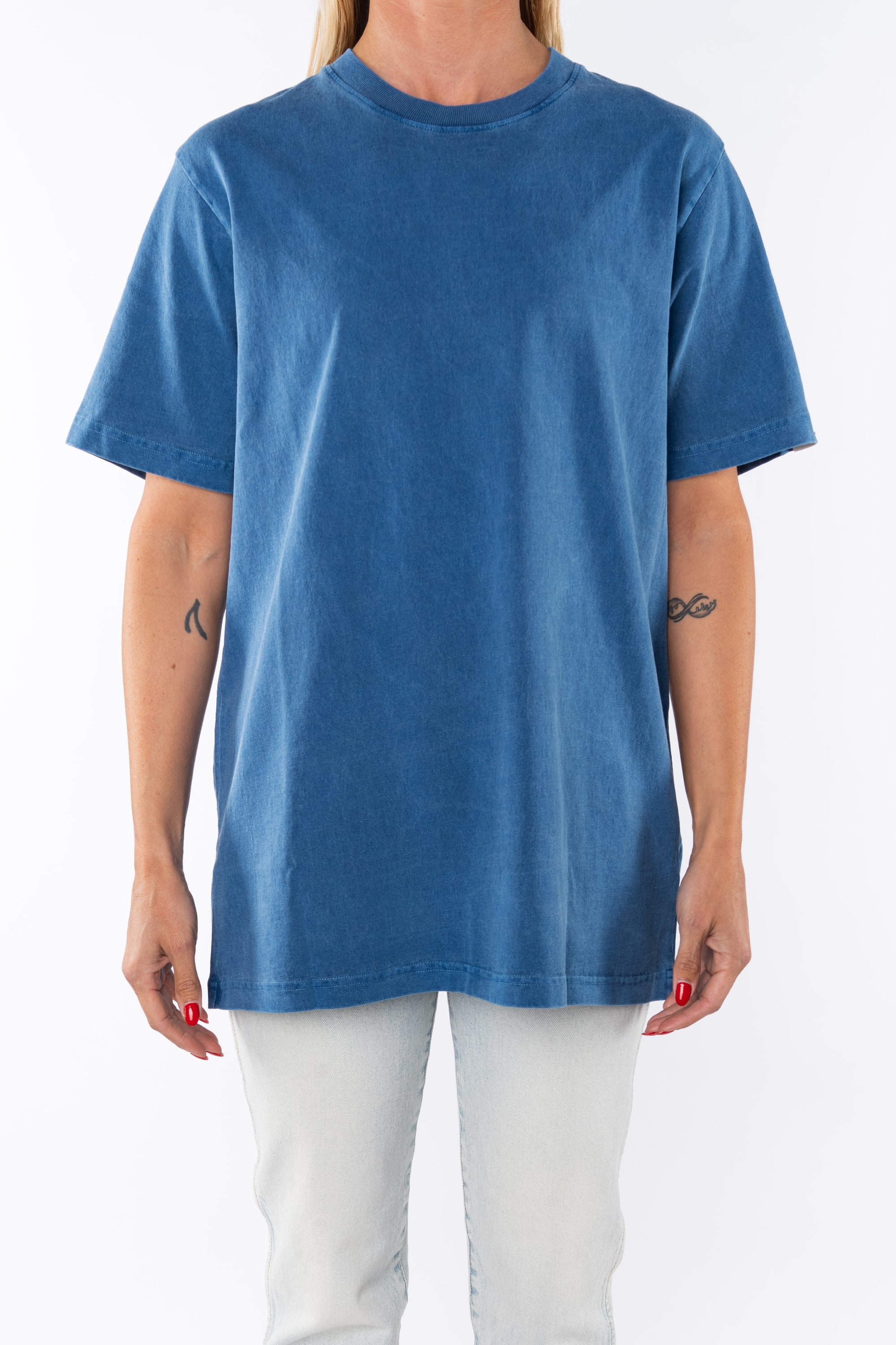 Woman wearing a teal beach t-shirt and light denim jeans on a white background