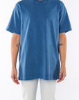 Woman wearing a teal beach t-shirt and light denim jeans on a white background