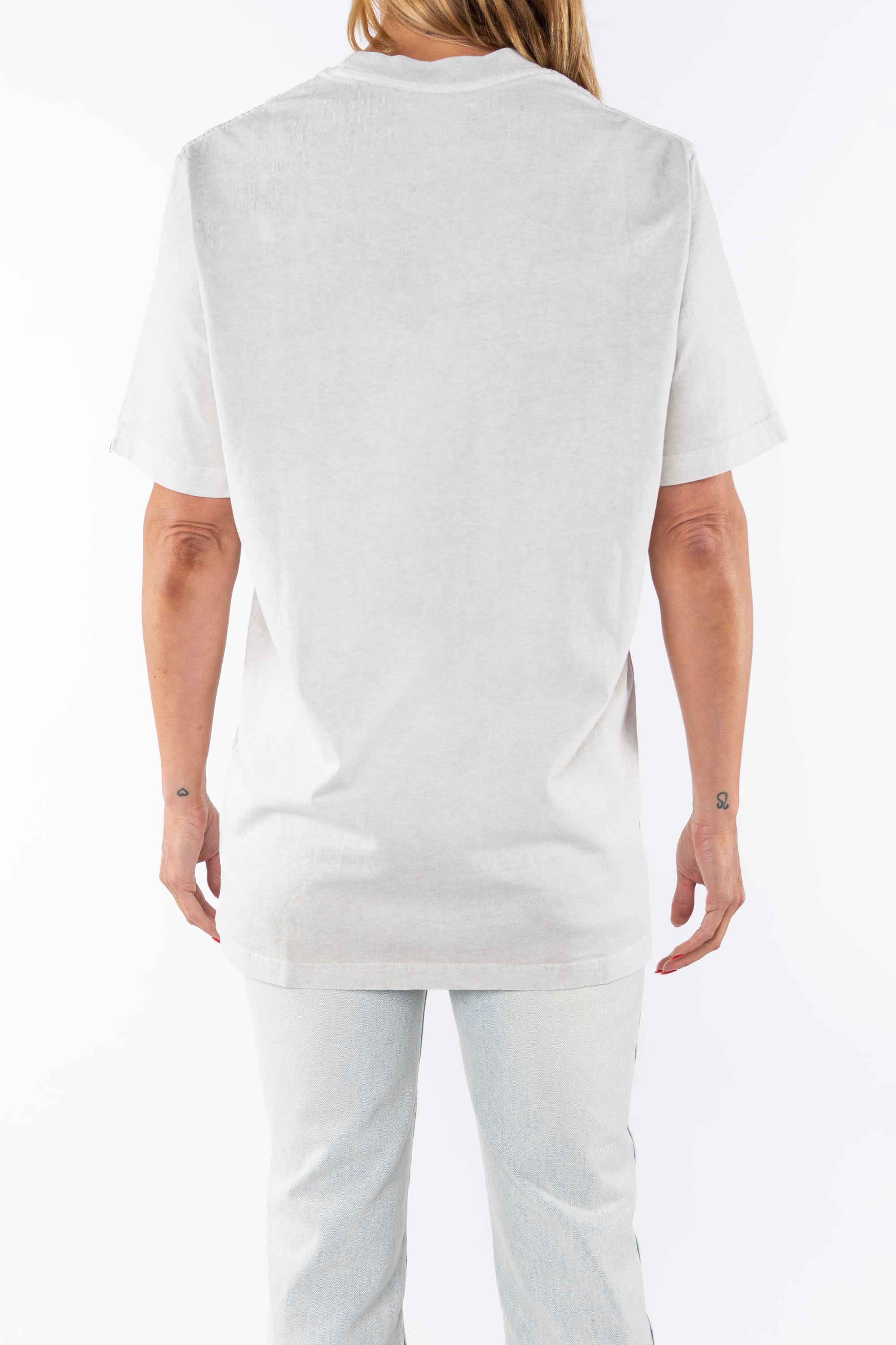 Back shot of a woman wearing an oversized Crewneck T-shirt in cream with light washed denim jeans.