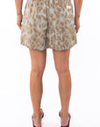 Back shot of a woman wearing leopard shorts on a white background. 
