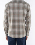 Back shot of a man wearing a lightweight flannel Plaid shirt in Green/Red with navy pants on a white background. 