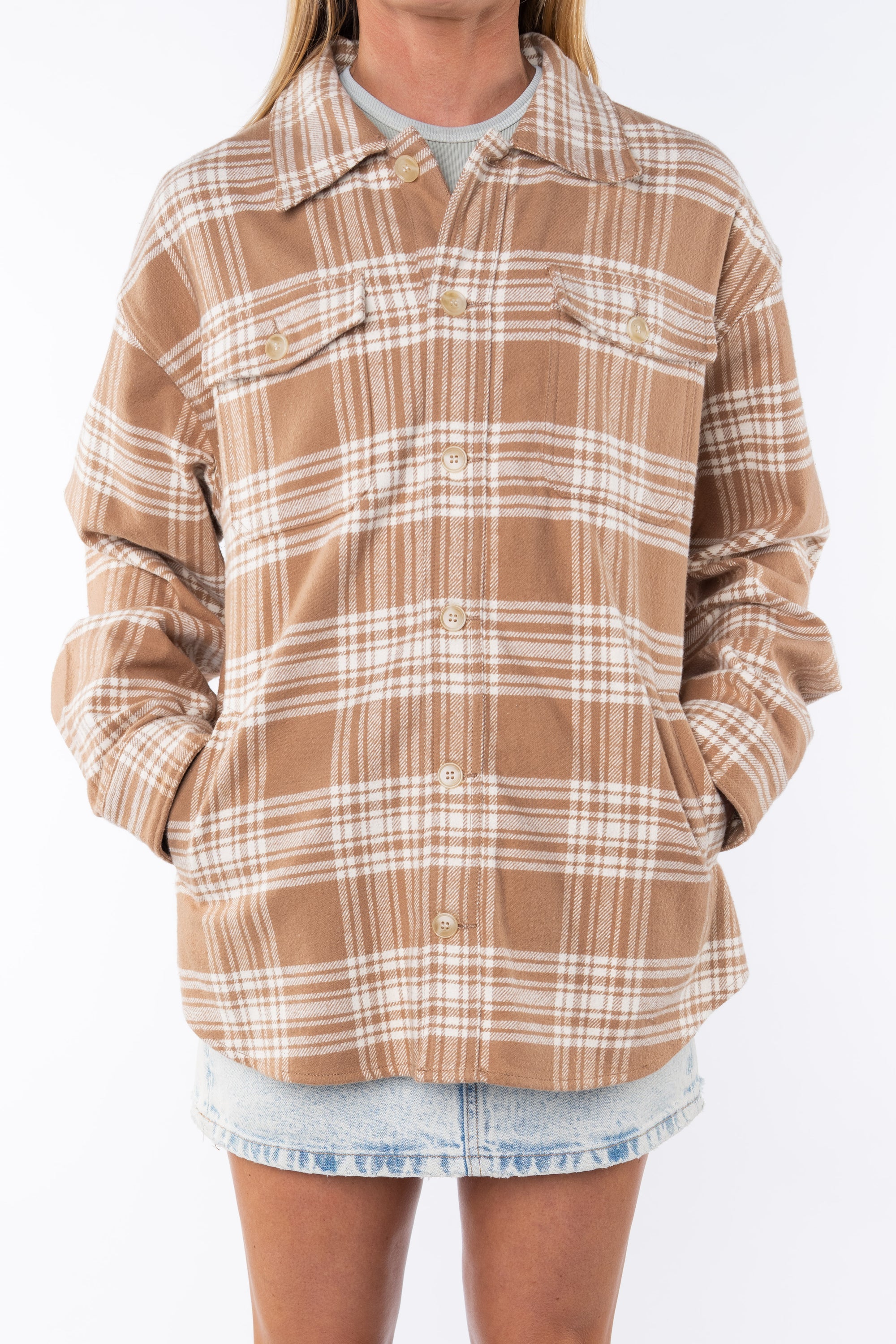 Woman wearing a flannel Split Hem Shirt Jacket in Beige/White Plaid with a crewneck Tank in cream and Denim mini Skirt on a white background. 