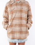Woman wearing a flannel Split Hem Shirt Jacket in Beige/White Plaid with a crewneck Tank in cream and Denim mini Skirt on a white background. 