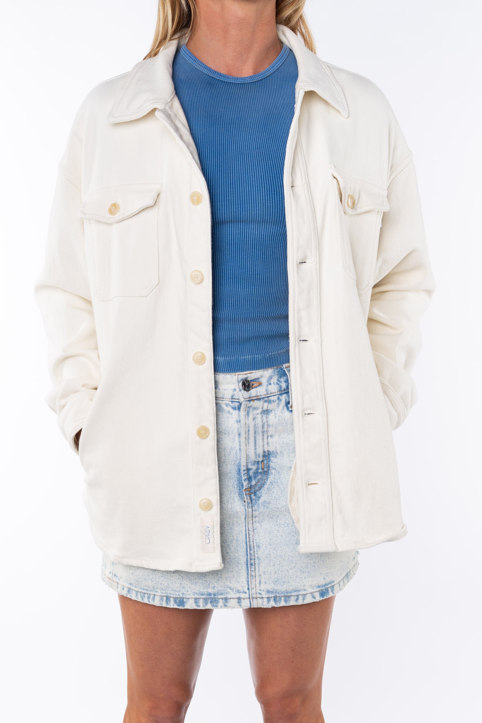 Woman wearing a Shirt Jacket in Beige with crewneck tank top in blue and the Denim mini Skirt.