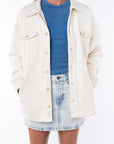 Woman wearing a Shirt Jacket in Beige with crewneck tank top in blue and the Denim mini Skirt.