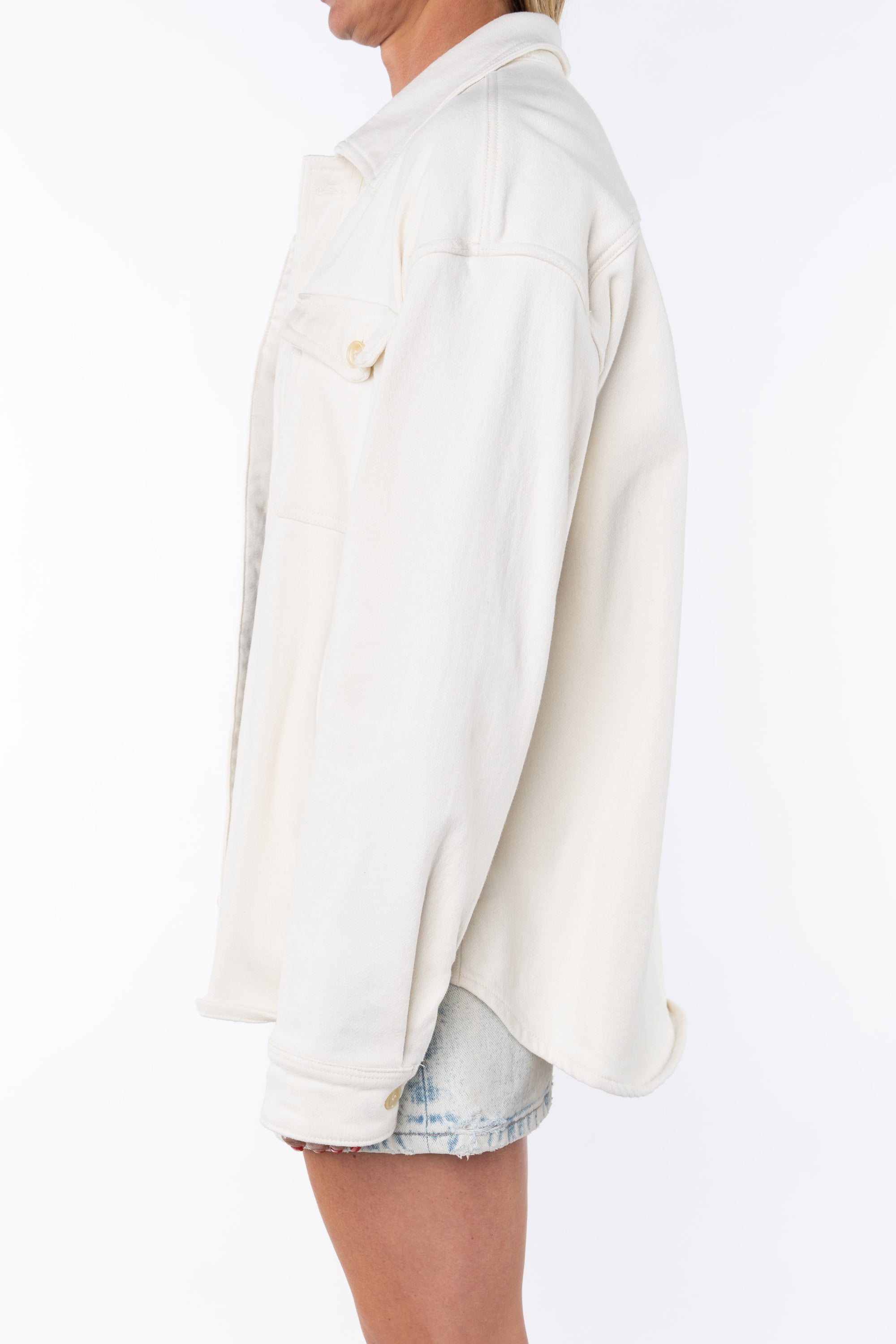 Side shot of a woman wearing Bucky Split Hem Shirt Jacket in Beige with Denim Day Skirt. 