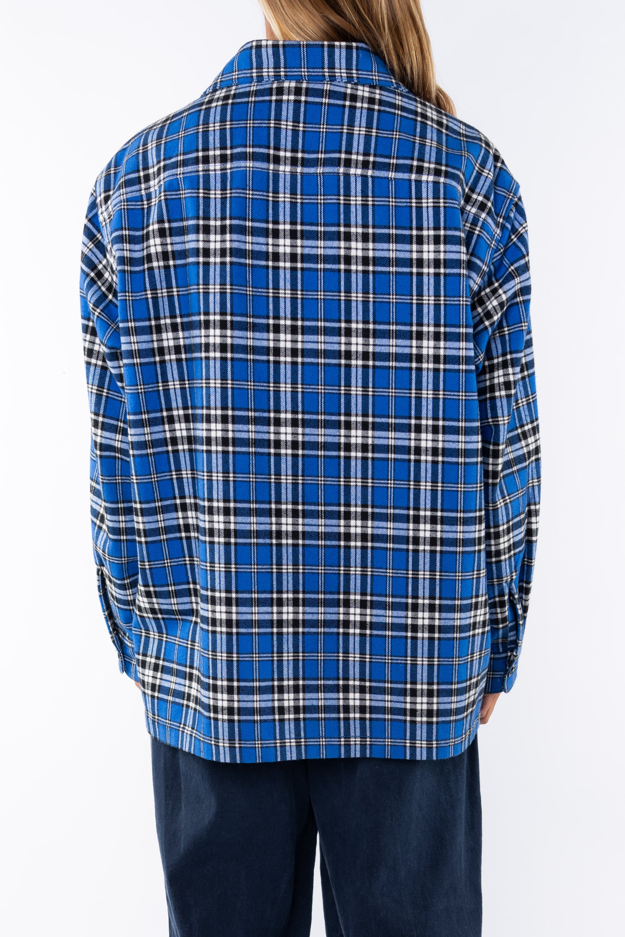 Back shot of woman wearing the Bucky Flannel Over shirt in blue/black and navy day pants. 