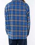 Back shot of woman wearing the Bucky Flannel Over shirt in blue/black and navy day pants. 