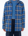 Woman wearing the Bucky Flannel Over shirt in blue/black with Scallop Tank in Blue Wave and navy day pants. 