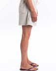 Side view of a woman wearing a light-gray french terry day shorts and sandals on a white background