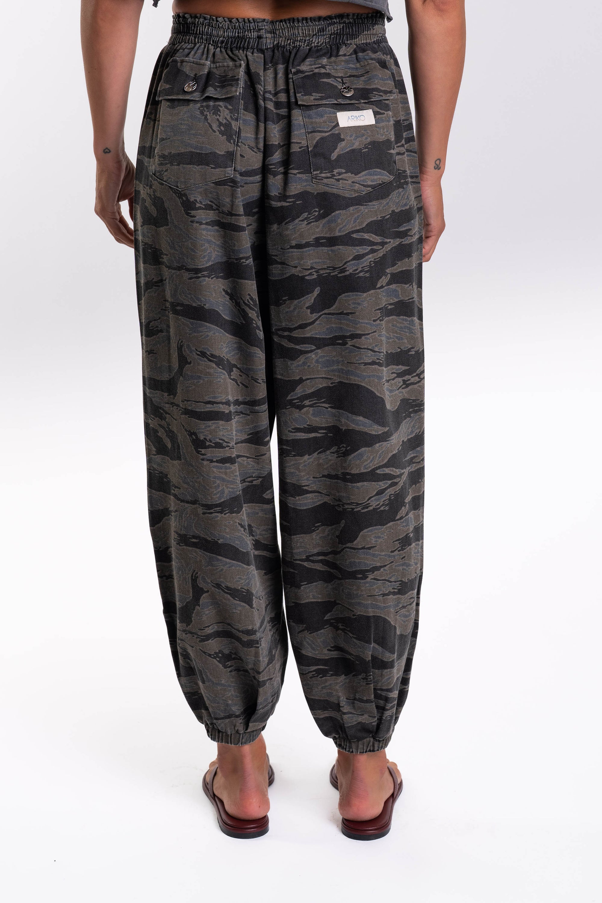 Back view of a woman wearing Ocean Tiger Camouflage pants worn on a white background