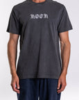 Person wearing a dark gray graphic t-shirt with 'KOOK' printed on it against a white background