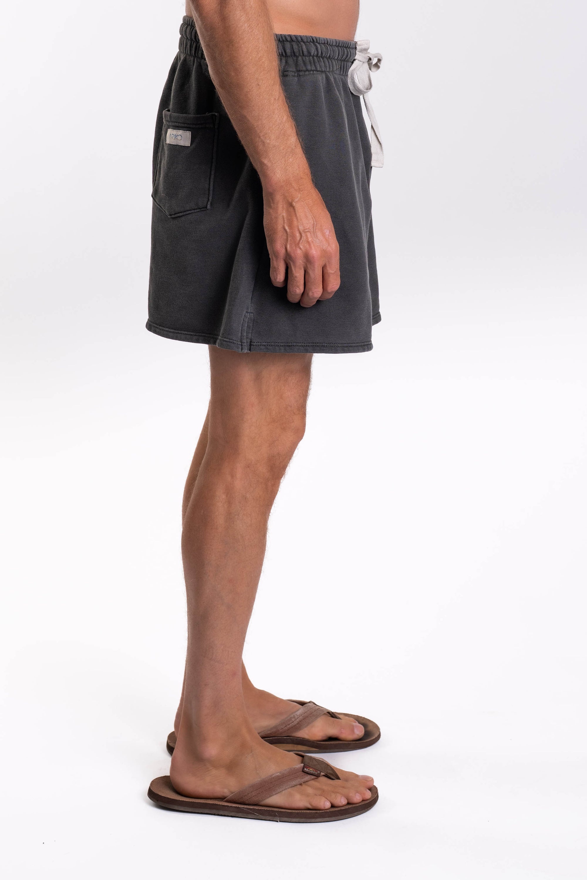 Side view of a person wearing dark gray shorts on a white background