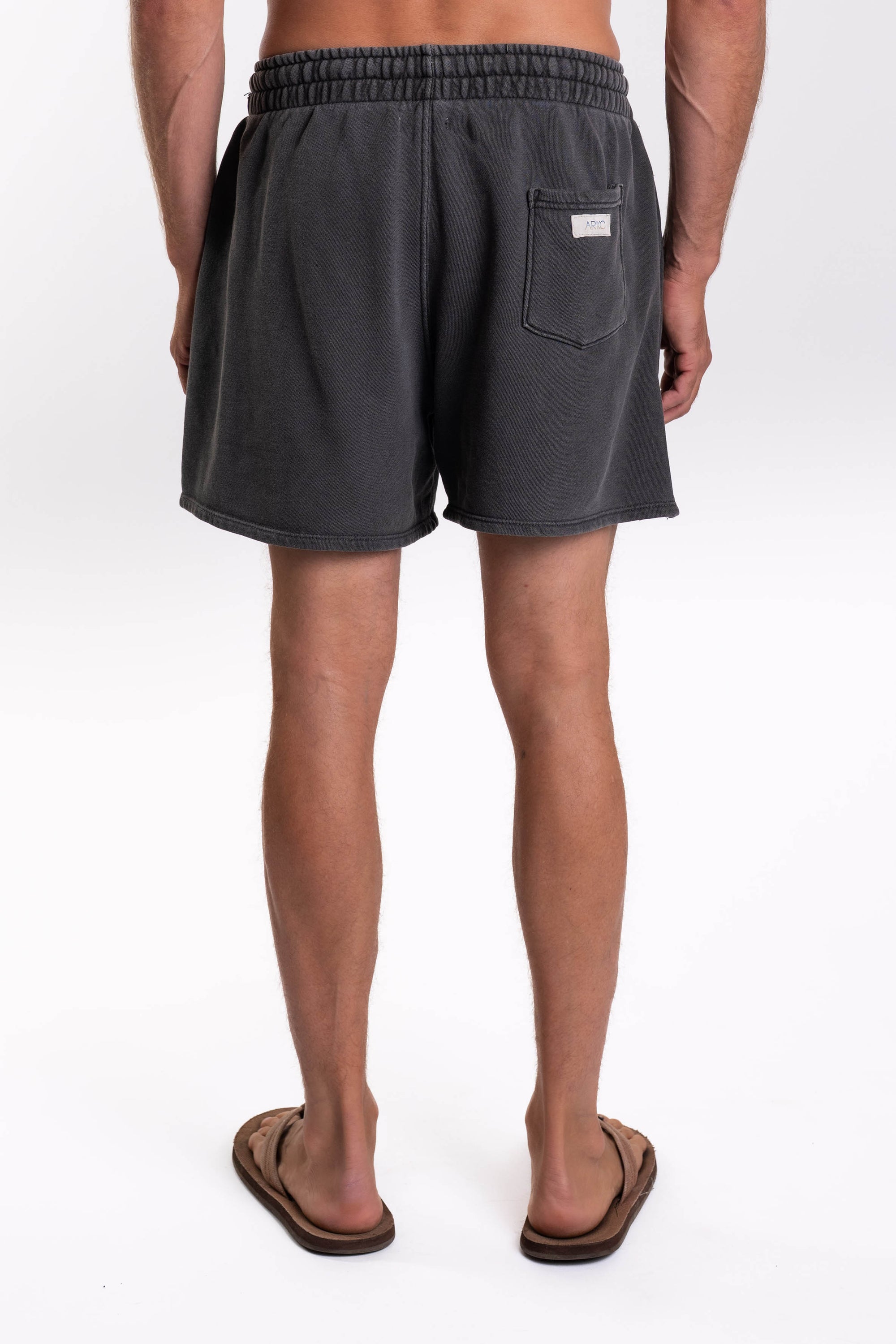 Back view of a person wearing dark gray french terry day shorts on a white background