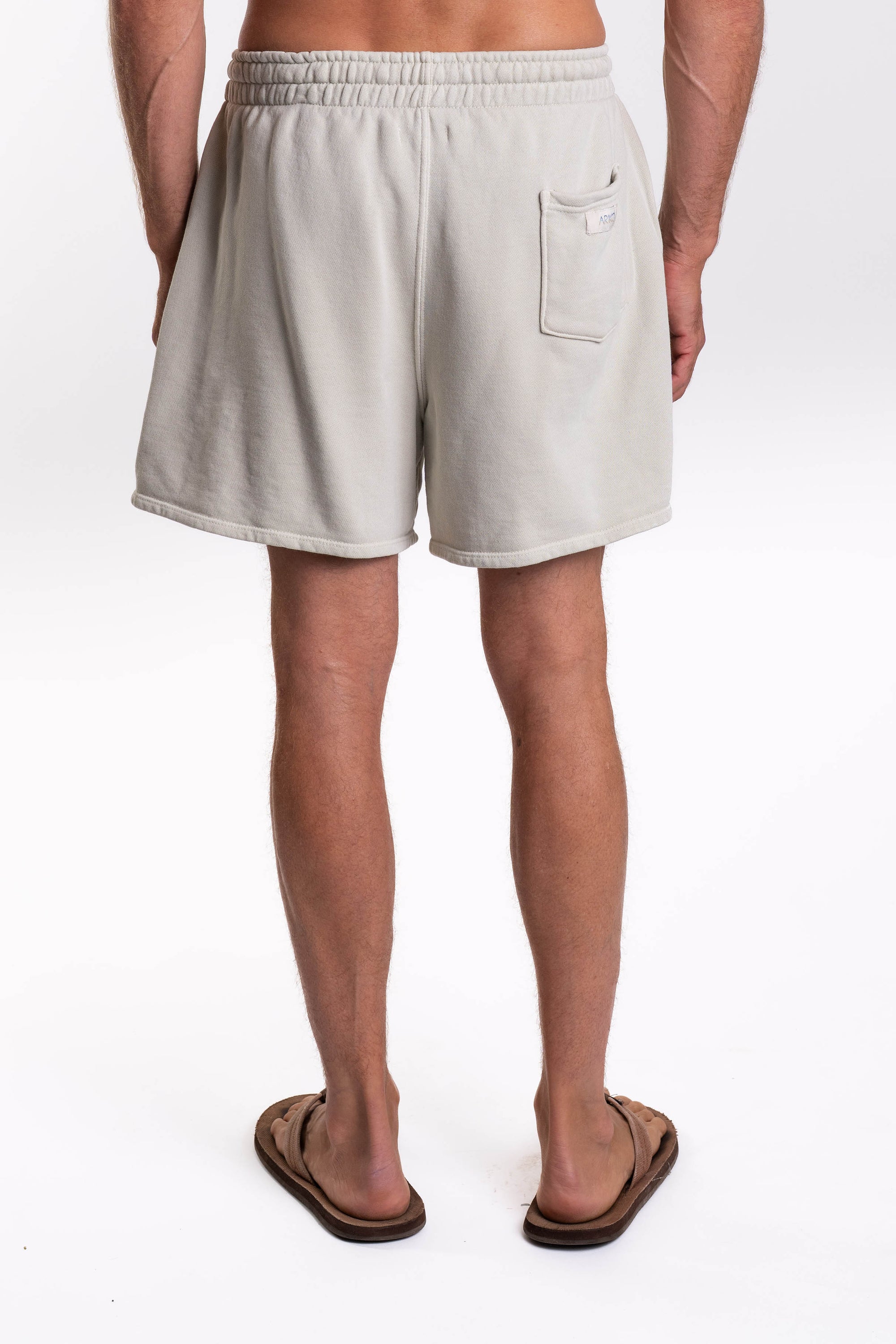 Back view of a man wearing light gray french terry day shorts on a white background